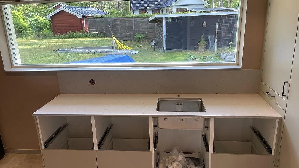Bänkskiva i ljus Silestone Concrete Pulse, matt Mocka-finish, med rostfri ho och stänkskydd i en tvättstuga i Åhus.