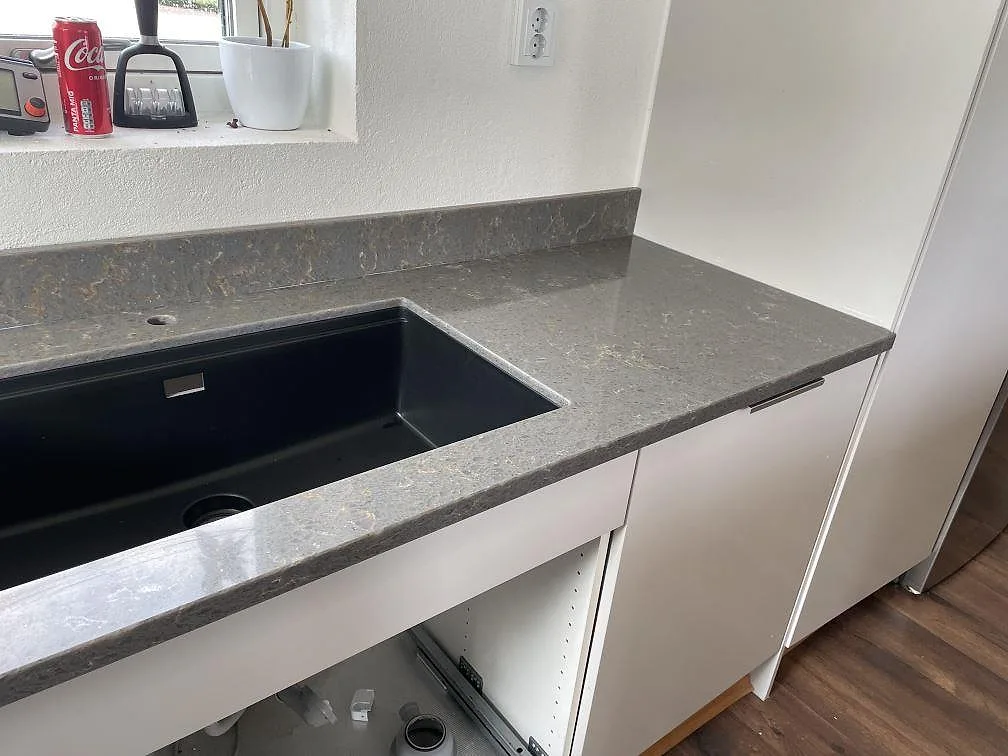 Köksbänkskiva i Silestone Cooper Mist, polerad grå komposit, med svart underlimmad diskho och stänkkant i Ystad.