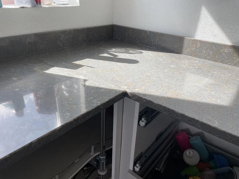 Detalj av polerad Silestone Cooper Mist i hörn med uppvikt stänkkant och ljus ådring i kök i Ystad.