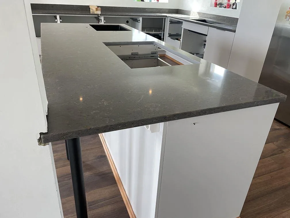 Halvö med köksbänkskiva i Silestone Cooper Mist, polerad komposit med mjuk ådring, i ett vitt kök i Ystad.