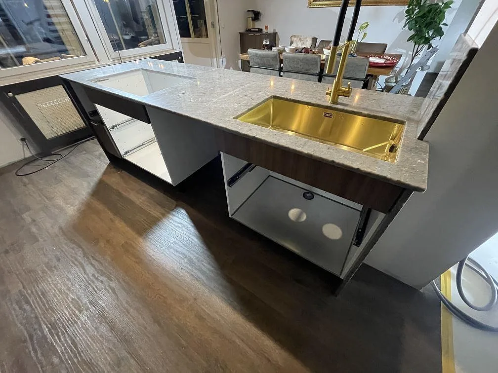 Köksbänkskiva i polerad Silestone Copper Mist med guldfärgad diskho och blandare i ett kök i Åkersberga.