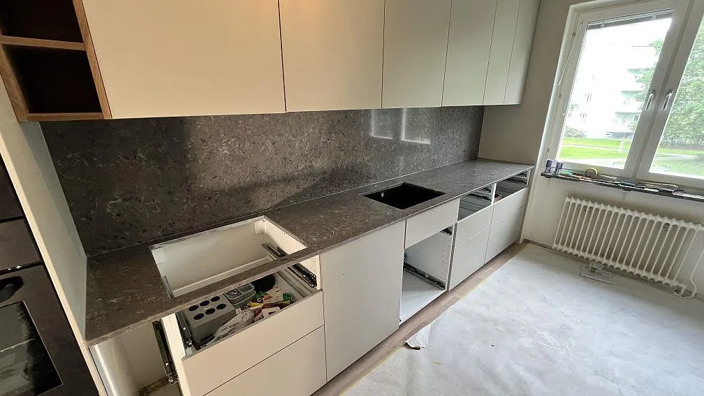 Köksbänkskiva i polerad Silestone Copper Mist komposit med matchande stänkskydd och synliga urtag i ett kök i Norrköping.