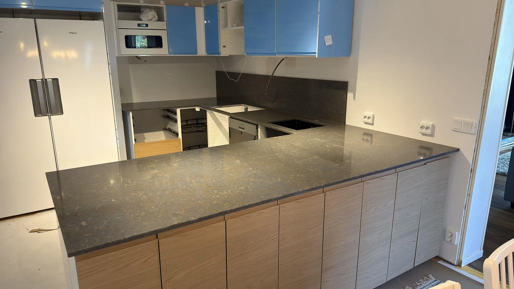 Köksbänkskiva i polerad Silestone Copper Mist, gråbrun kvartskomposit, med stor arbetsyta och låg stänkkant i ett kök i Örebro.