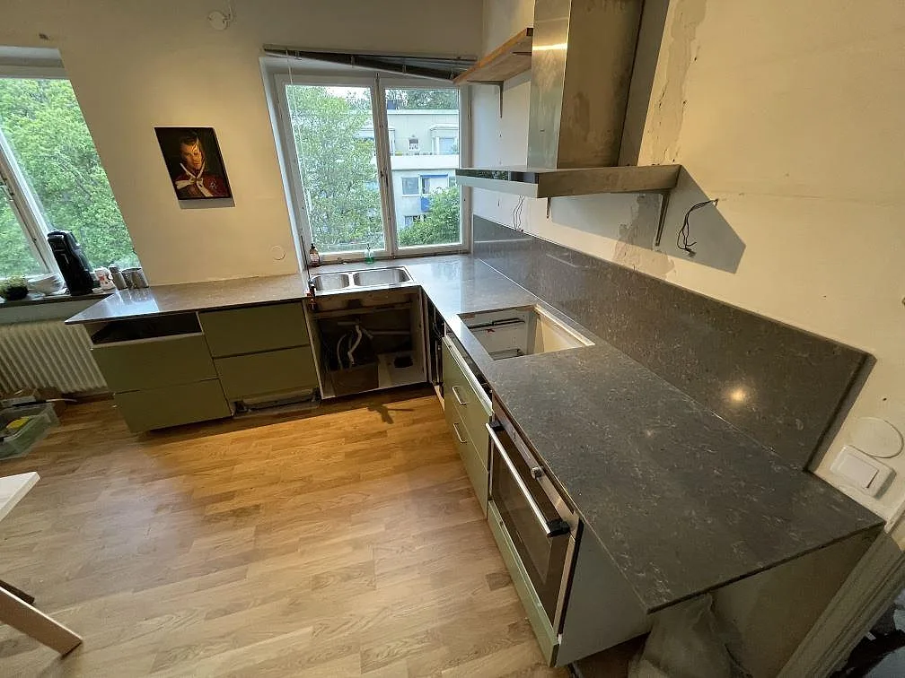 Polerad kompositbänkskiva i Silestone Copper Mist med låg stänkkant och lång arbetsyta under fläkten i Stockholm.