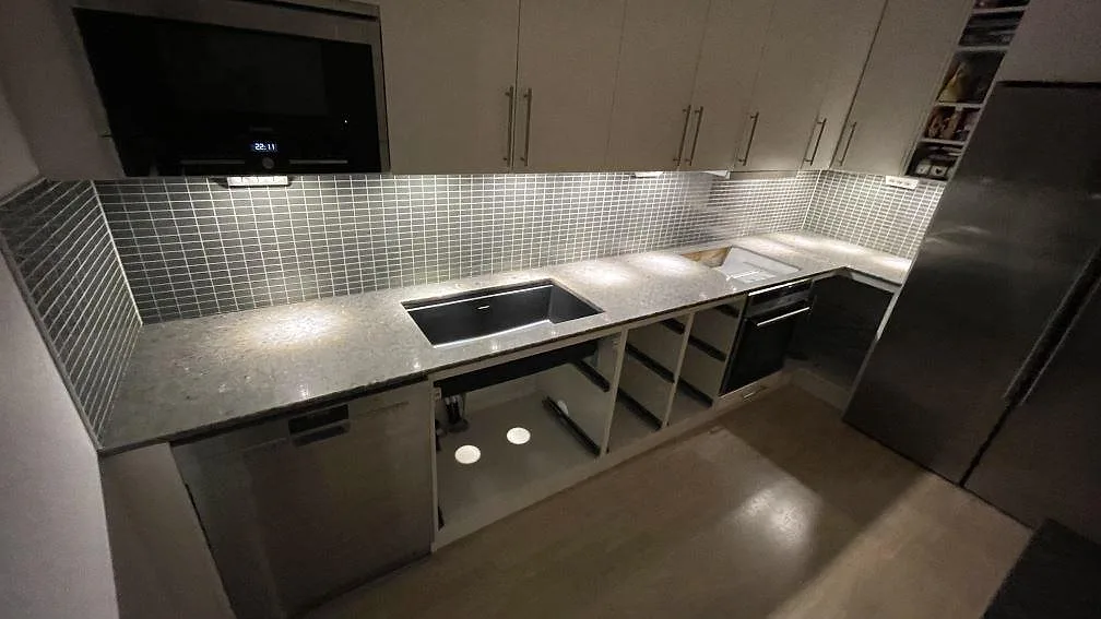 Köksbänkskiva i Silestone Copper Mist, polerad komposit, med underlimmad mörk diskho och öppning för häll i ett kök i Växjö.