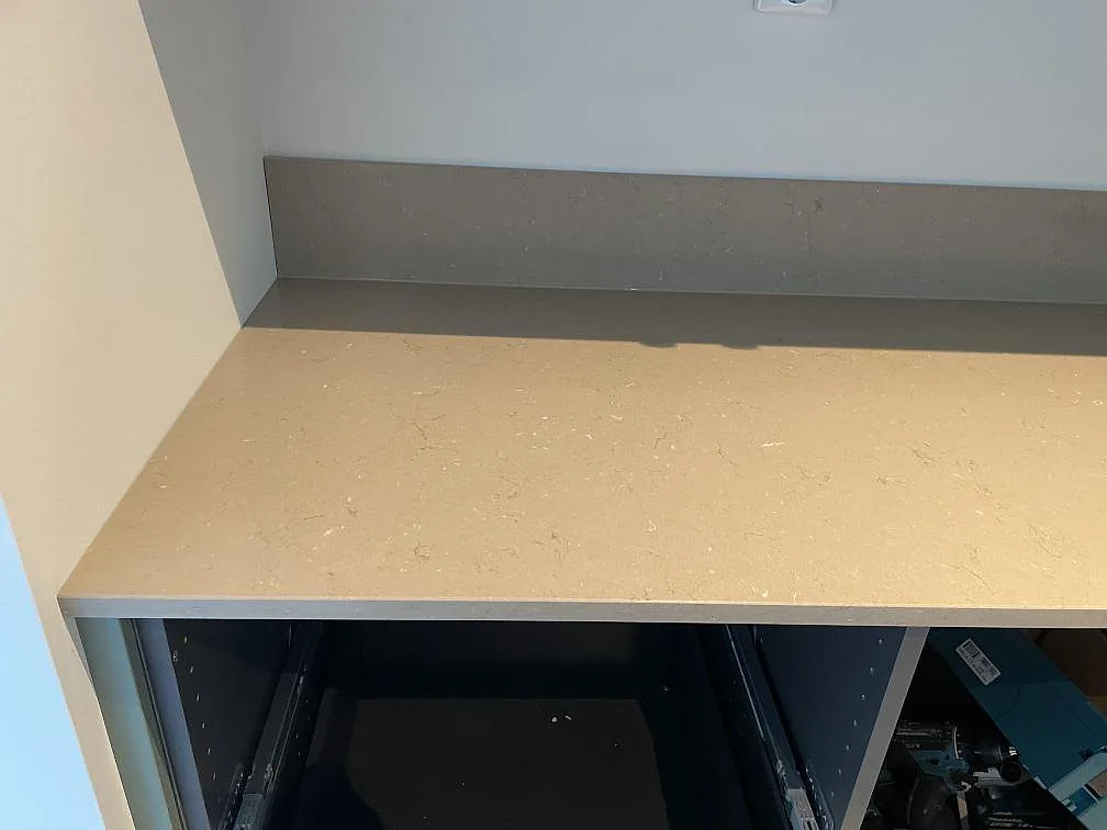 Rak köksbänkskiva i polerad Silestone Coral Clay komposit med stänkkant och öppna köksstommar i Skurup.