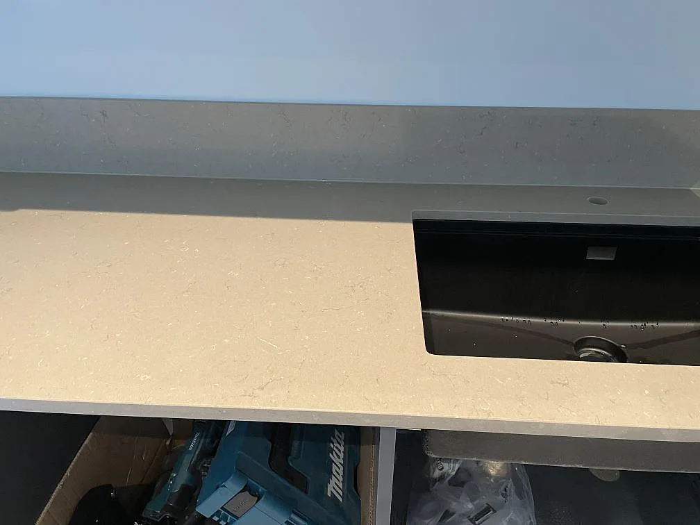 Polerad köksbänkskiva i Silestone Coral Clay komposit med svart underlimmad diskho och uppvikt stänkkant i Skurup.