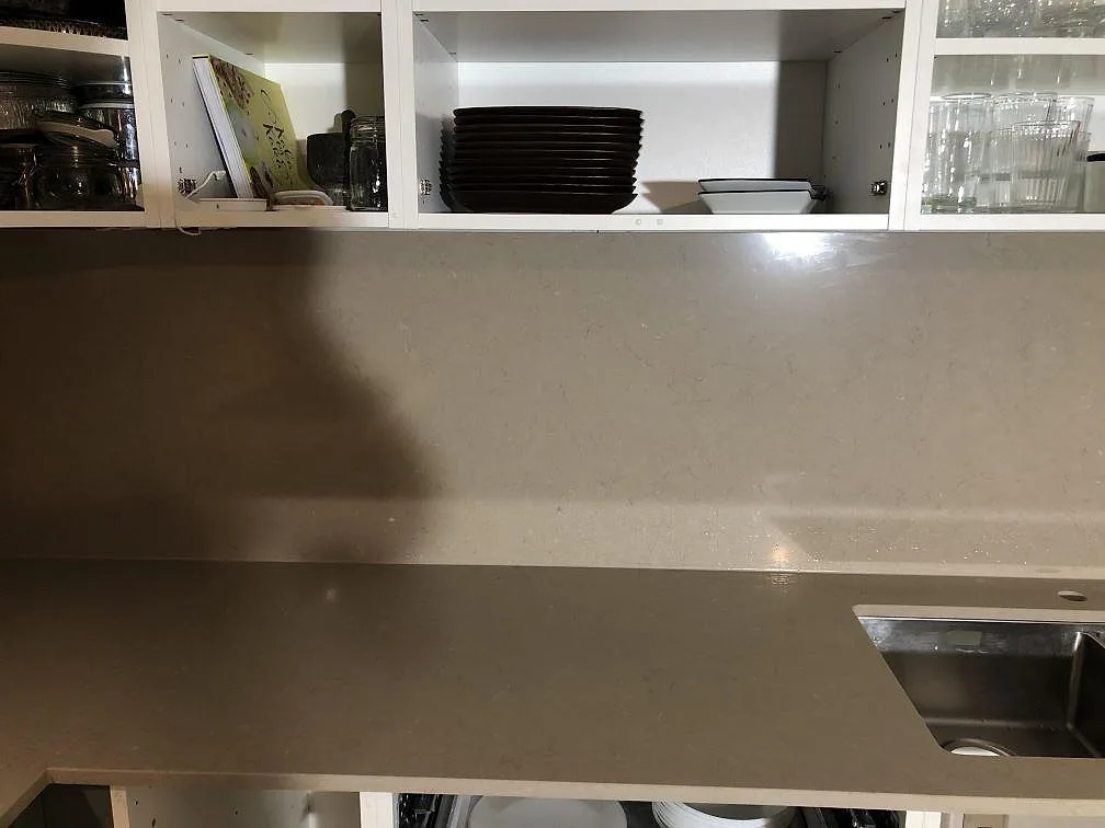 Närbild på underlimmad rostfri dubbelho infälld i polerad Silestone Coral Clay köksbänkskiva i taupe i Åkarp.