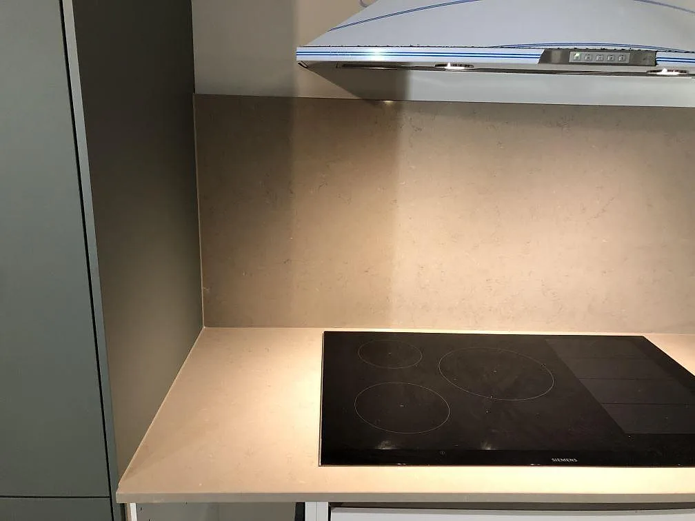 Polerad köksbänkskiva i varm taupe Silestone Coral Clay med fin melering och uppvikt stänkkant under överskåp i ett kök i Åkarp.