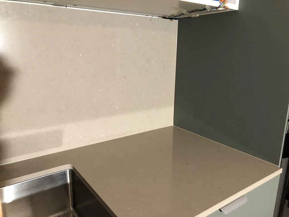 Hörn av polerad köksbänkskiva i Silestone Coral Clay med integrerad uppvikt stänkkant och underlimmad rostfri diskho i ett kök i Åkarp.