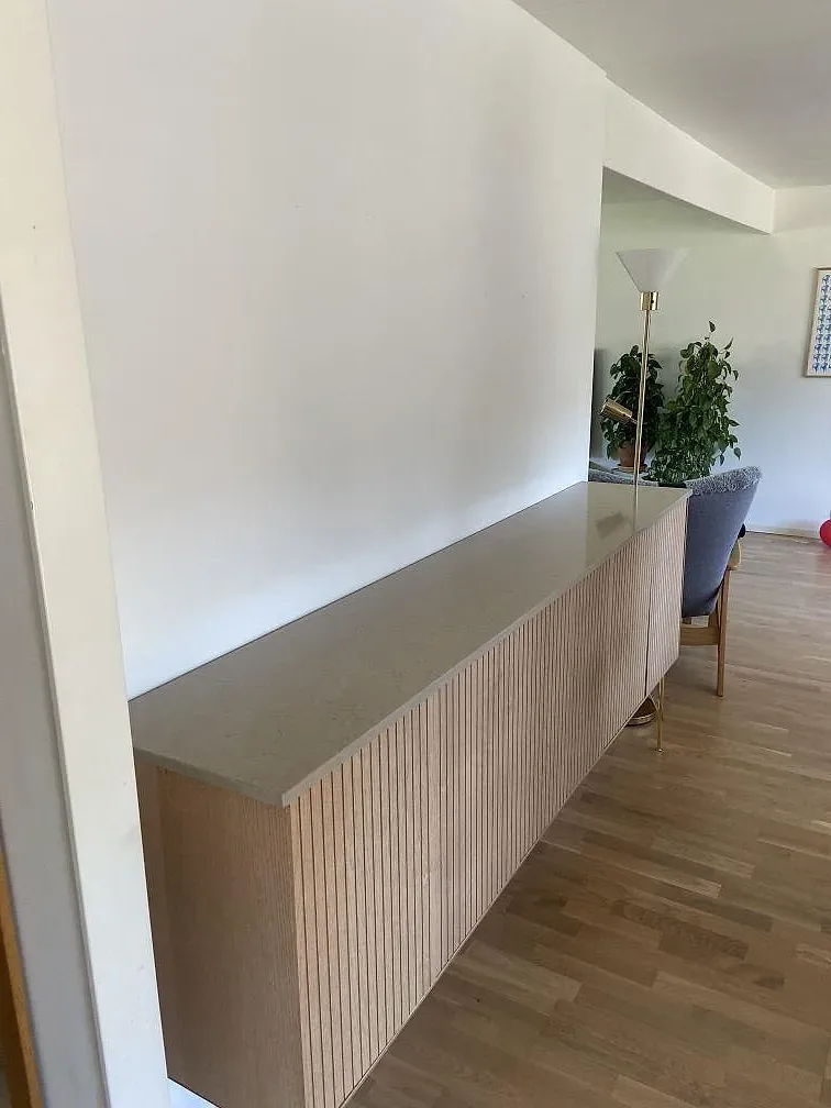 Bänkskiva i varmgrå Silestone Coral Clay komposit, polerad, ovanpå en platsbyggd träinredning i Åkarp.