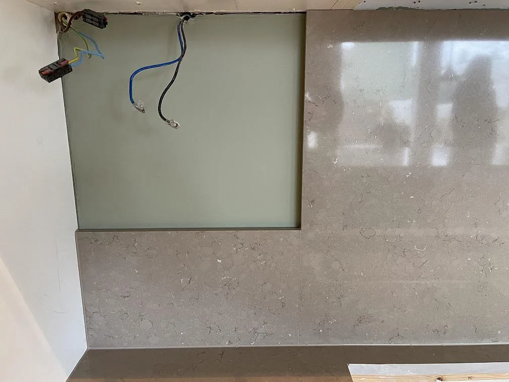 Stänkskydd i Silestone Coral Clay mot ett frostat glasparti i ett kök i Älta, fotograferat under montering.