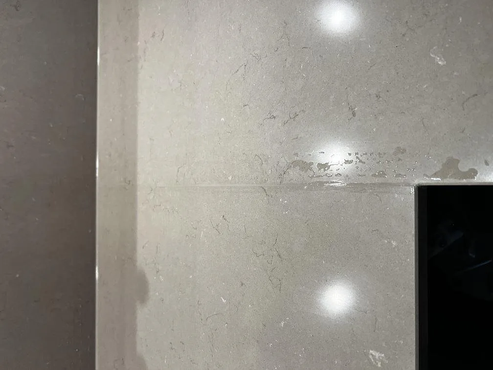 Närbild på den polerade ytan i Silestone Coral Clay med mjuk grå ådring och en skivskarv i ett kök i Ängelholm.