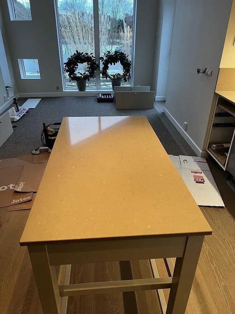 Köksö i polerad Silestone Coral Clay sedd ovanifrån i ett kök i Ängelholm under montering.