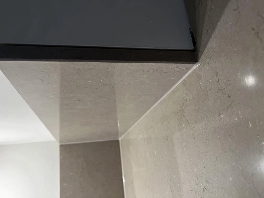 Hörndetalj där stänkkanten i Silestone Coral Clay möter induktionshällen i ett kök i Ängelholm.
