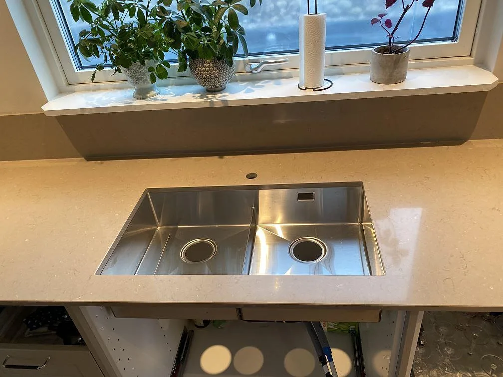 Underlimmad rostfri dubbelho i en polerad Silestone Coral Clay köksbänkskiva sedd ovanifrån vid fönsterbänken i ett kök i Alingsås.