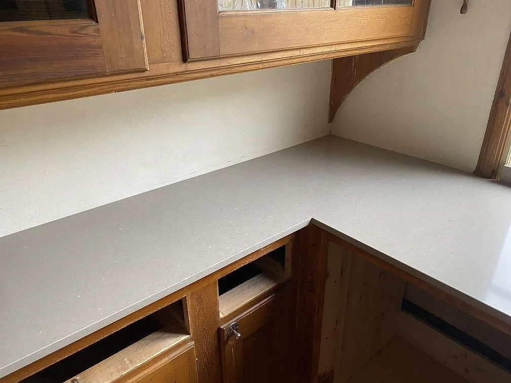 Närbild på hörndel i polerad Silestone Coral Clay med varm träinredning i kök i Allingsås.