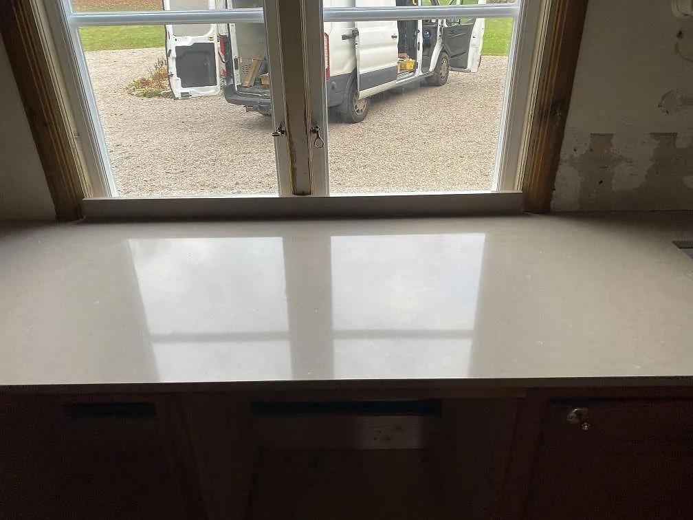 Fönsterbänk och bänkdel i polerad Silestone Coral Clay framför köksfönster i Allingsås.