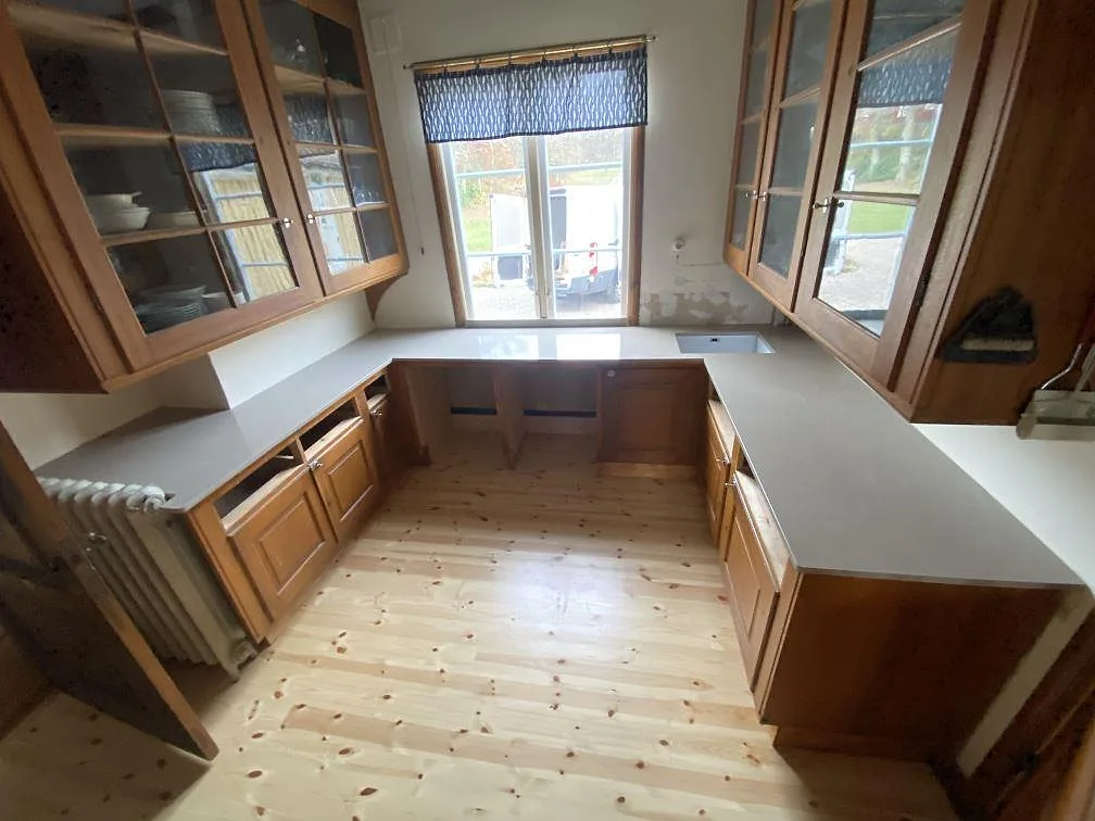 U-format kök i Allingsås med polerad Silestone Coral Clay som köksbänkskiva på traditionell träinredning.