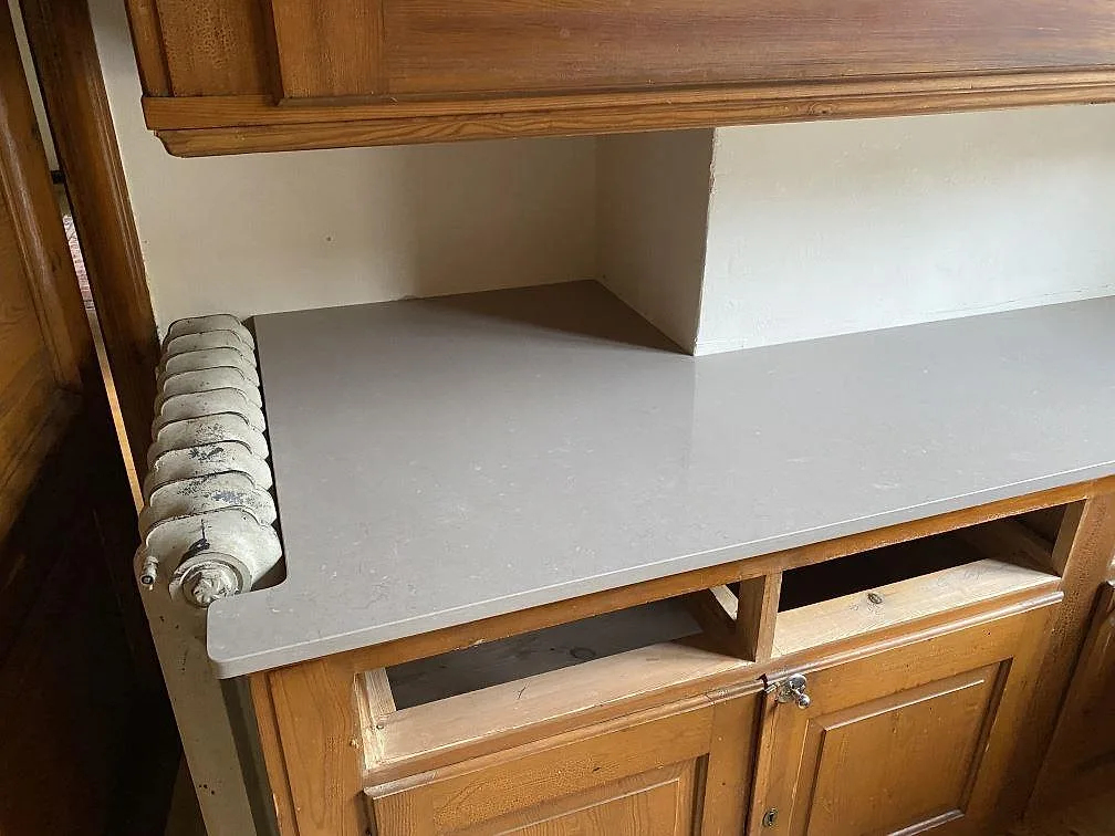 Detalj av polerad Silestone Coral Clay med urtag runt radiator och träskåp i kök i Allingsås.
