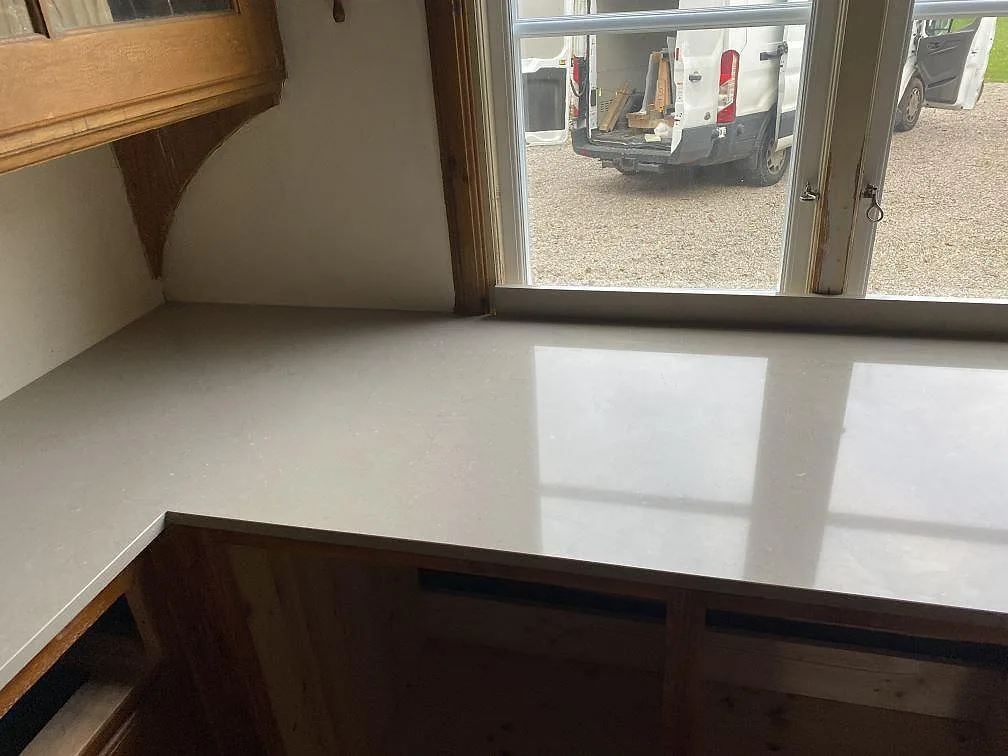 Polerad köksbänkskiva i Silestone Coral Clay vid fönster med spegling i stenen i Allingsås.
