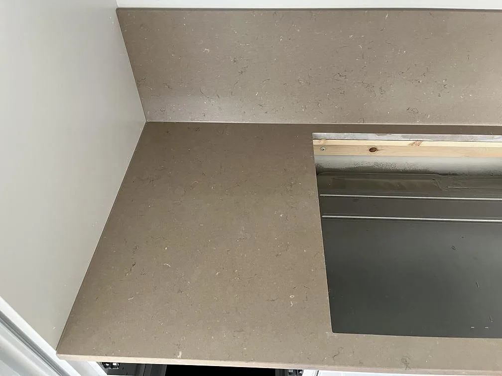 Hörnparti av köksbänkskiva i Silestone Coral Clay med uppvikt stänkkant i ett kök i Båstad.