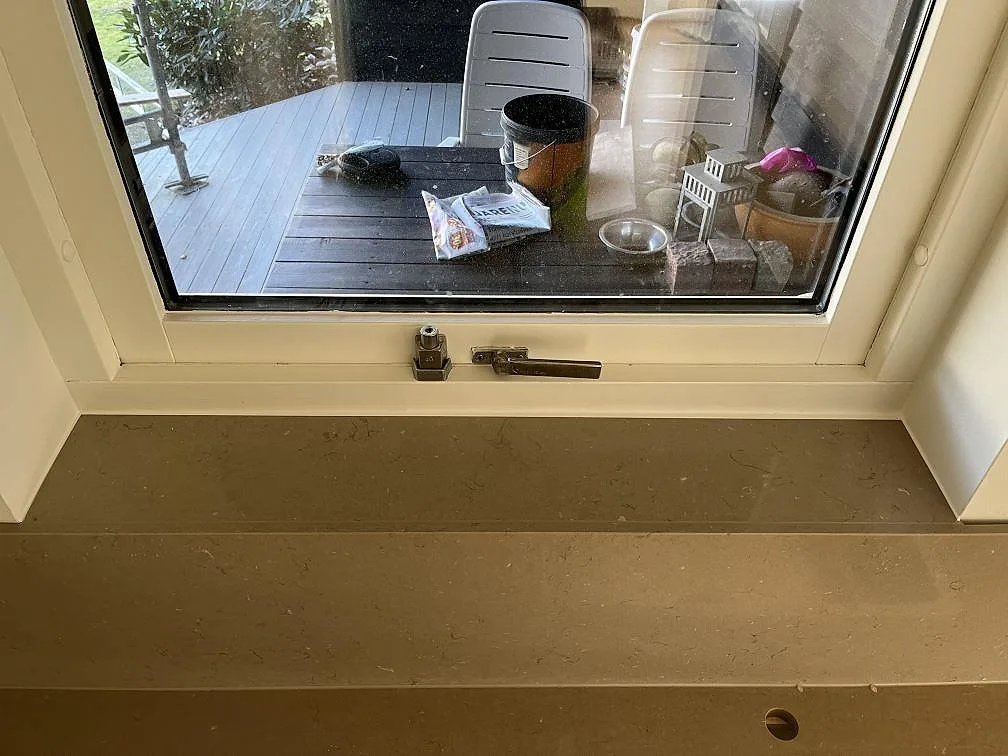 Fönsterbänk i Silestone Coral Clay i greige komposit vid ett köksfönster i Båstad.