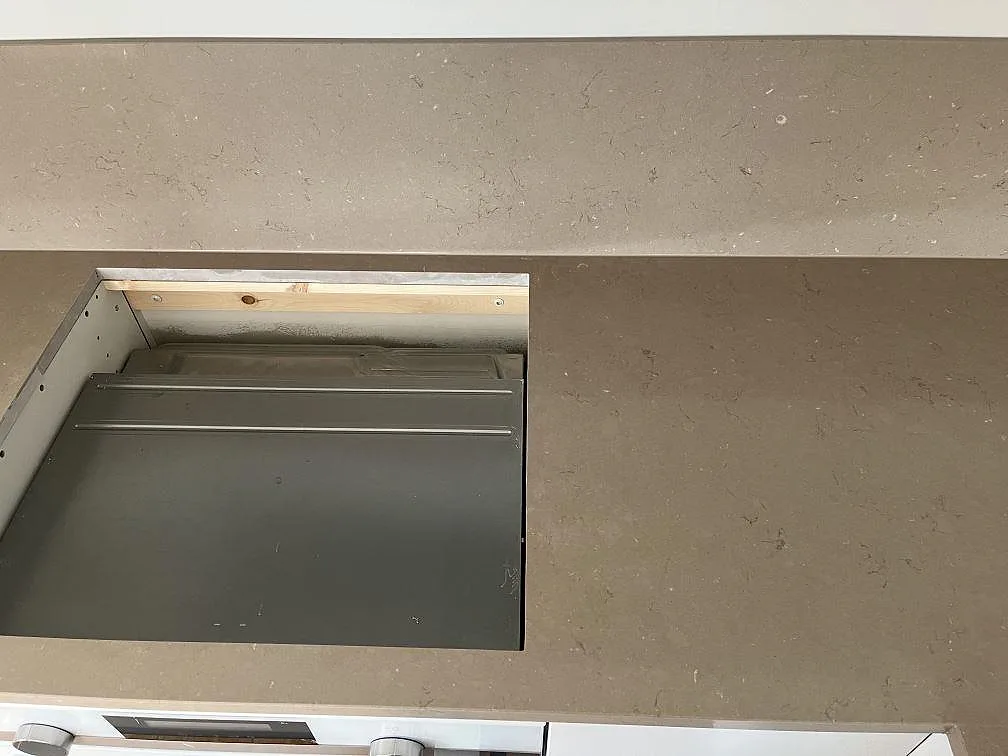 Bänkskiva i greige Silestone Coral Clay med urtag för induktionshäll i ett kök under montering i Båstad.
