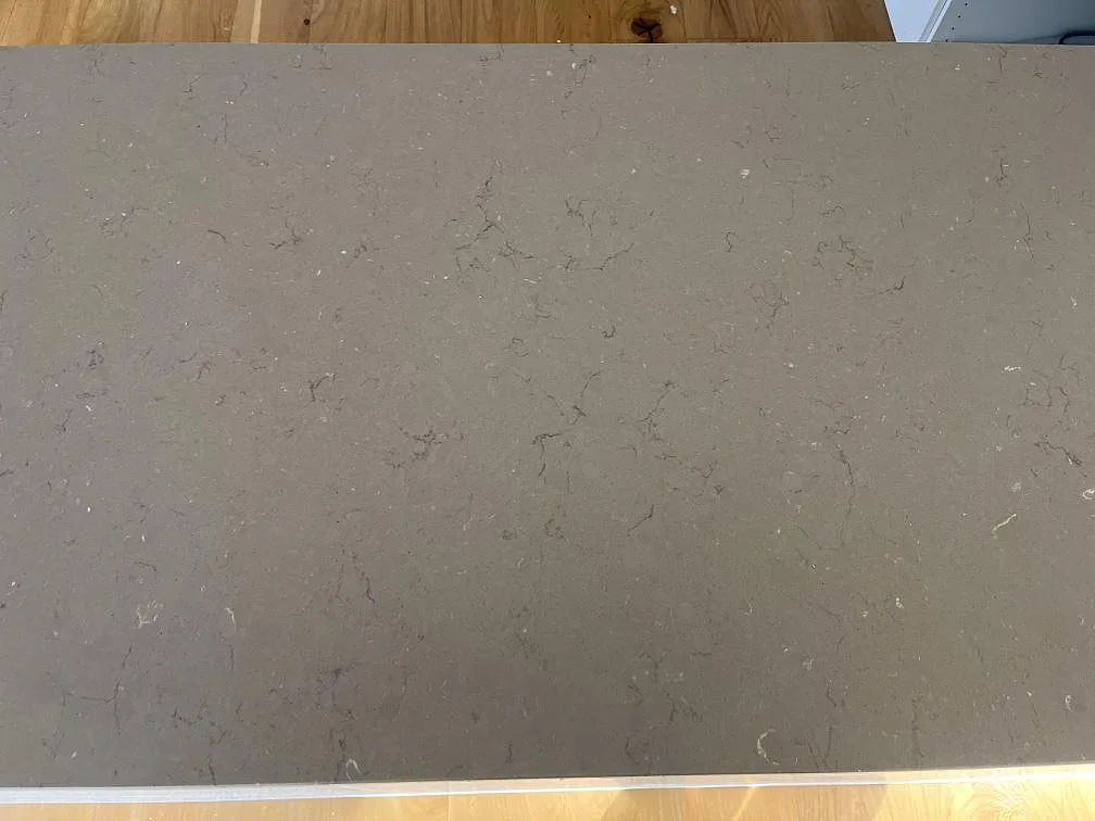 Bred köksbänkskiva i greige Silestone Coral Clay med diskret ådring i ett kök i Båstad.