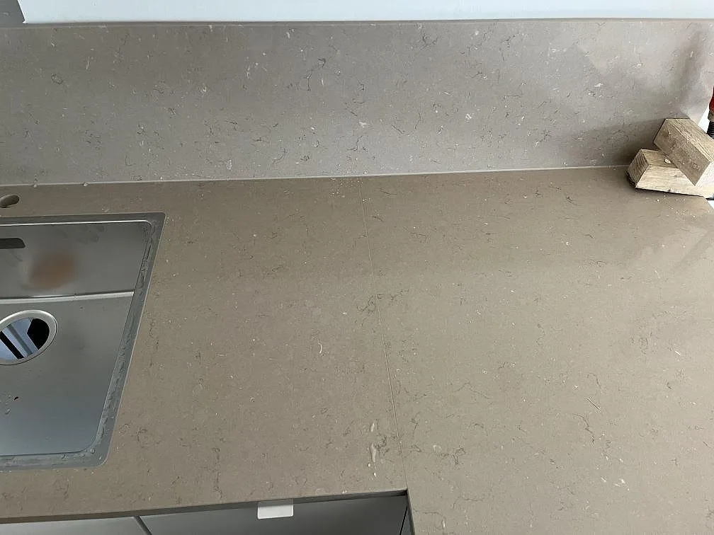 Köksbänkskiva i Silestone Coral Clay med rostfri diskho och uppvikt stänkkant i greige komposit i ett kök i Båstad.