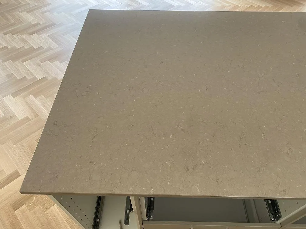 Närbild av varm gråbeige Silestone Coral Clay komposityta, polerad, på en köksö under montering i Båstad.
