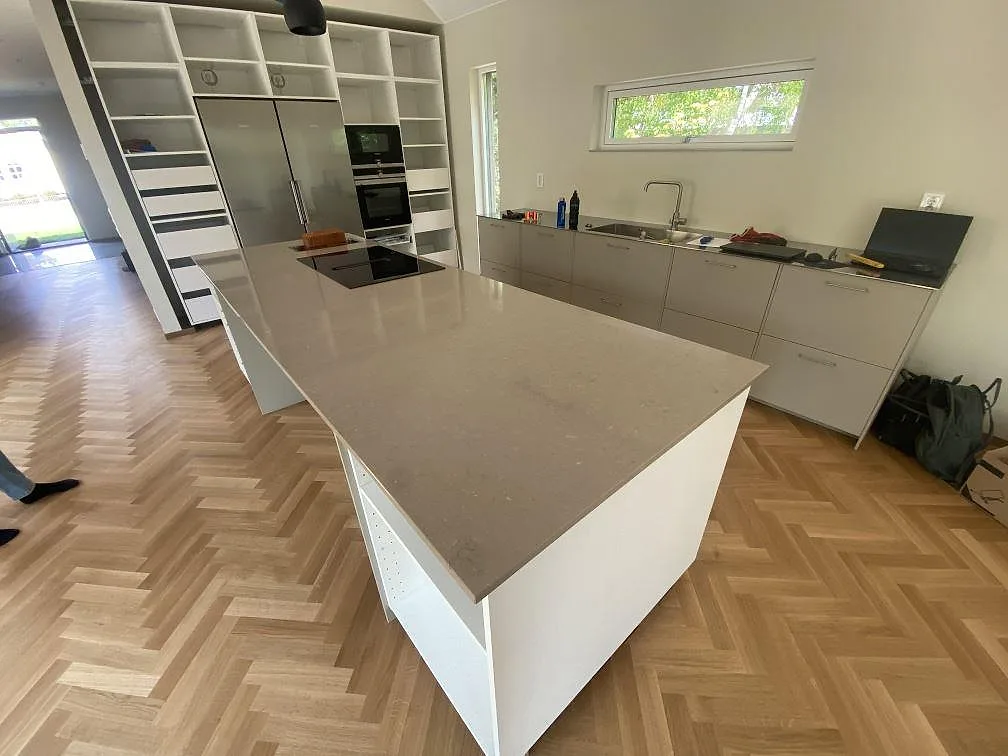 Köksbänkskiva i polerad Silestone Coral Clay komposit på stor köksö och väggbänkar i ett kök i Båstad.