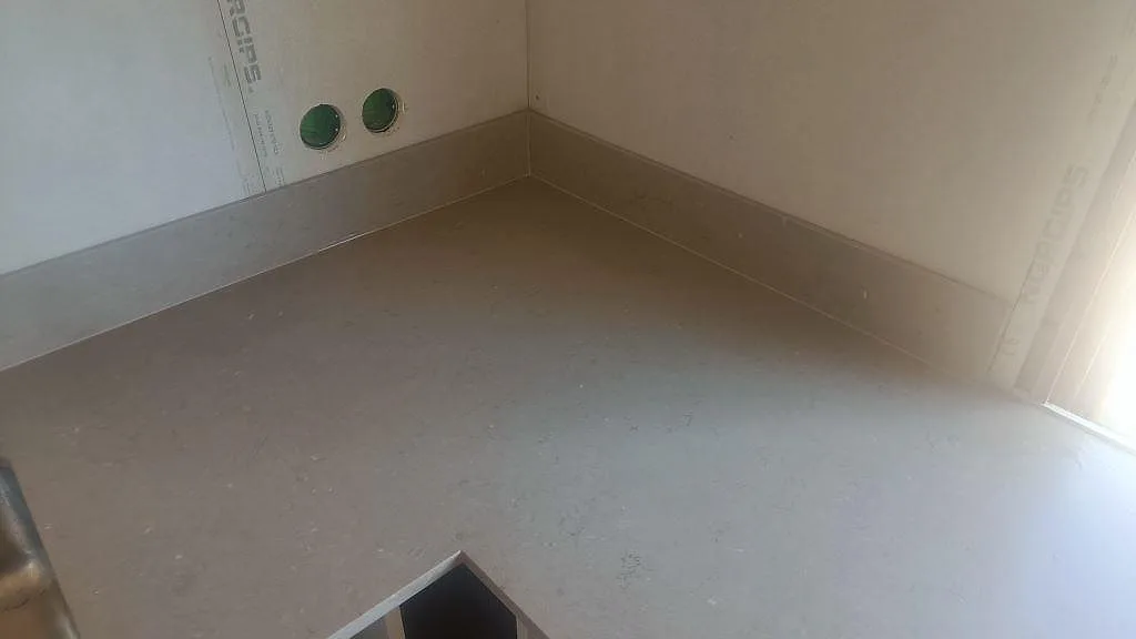 Hörnparti i matt Silestone Coral Clay med uppvikt stänkskydd och diskhodel i kök i Båstad.