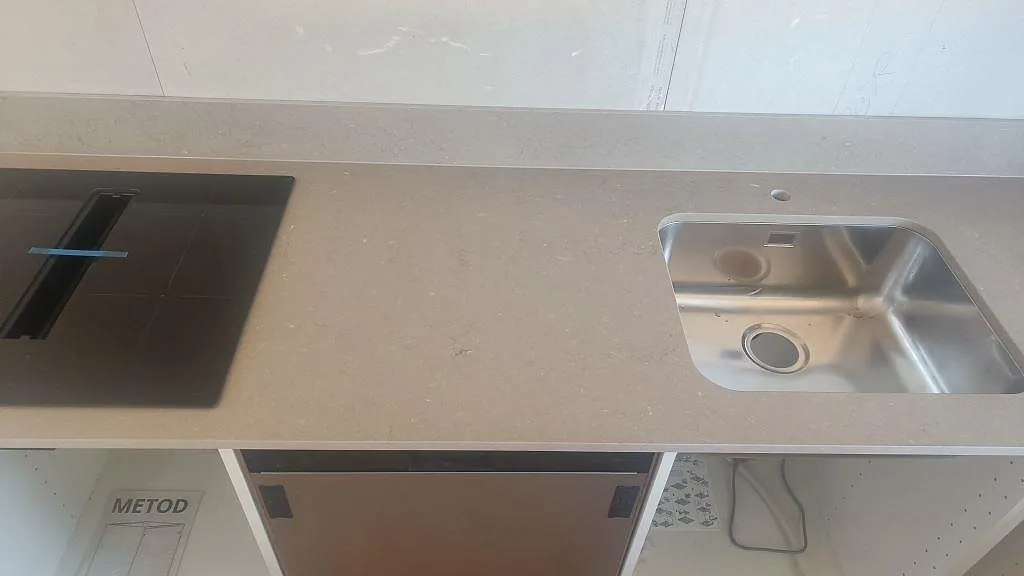 Närbild på matt Silestone Coral Clay komposit med svart häll och rostfri underlimmad diskho i kök i Båstad.