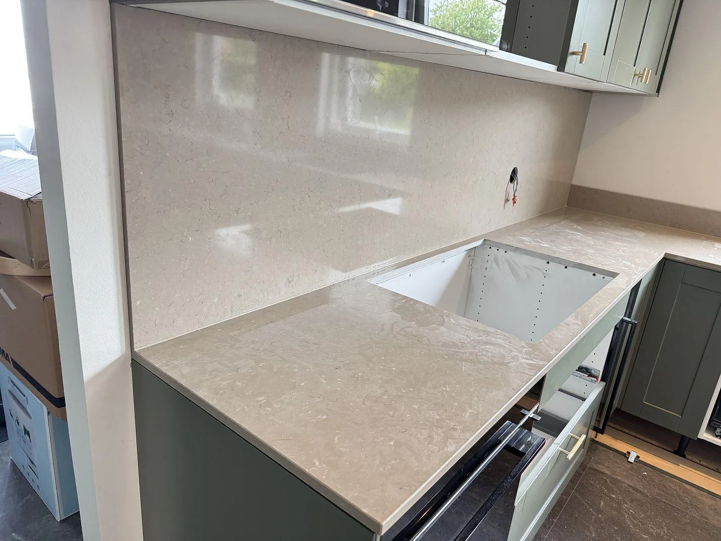 Köksbänkskiva och väggbeklädnad i polerad Silestone Coral Clay, kvartskomposit, med öppen diskhozon i ett kök i Bara.