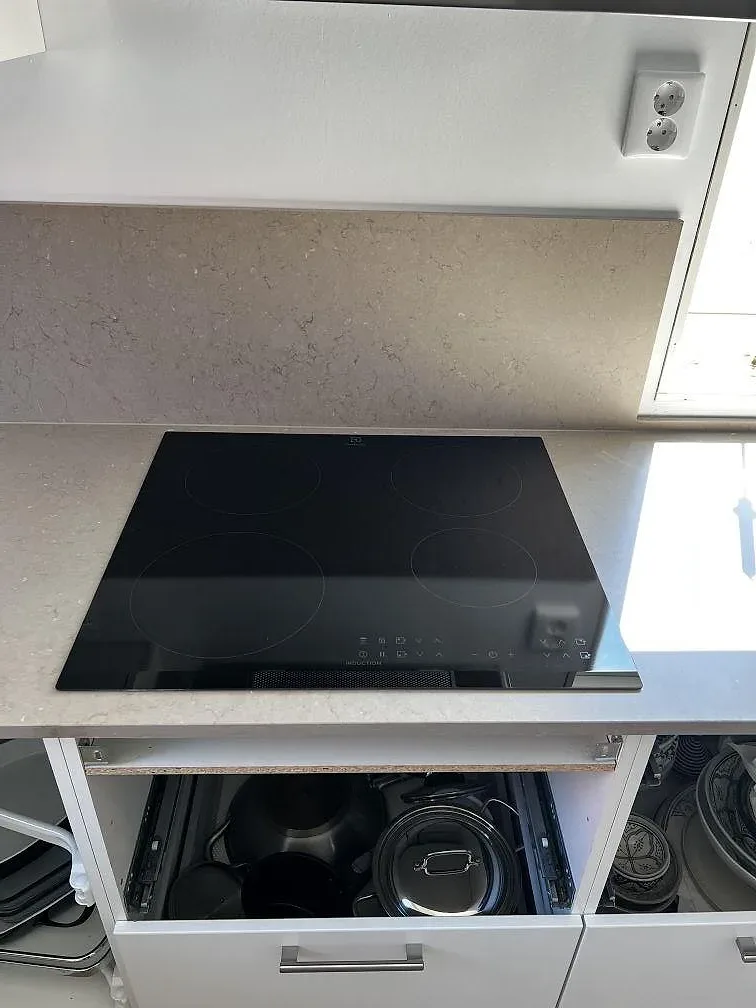 Infälld induktionshäll i matt Silestone Coral Clay köksbänkskiva intill fönster i ett kök i Barsebäck.