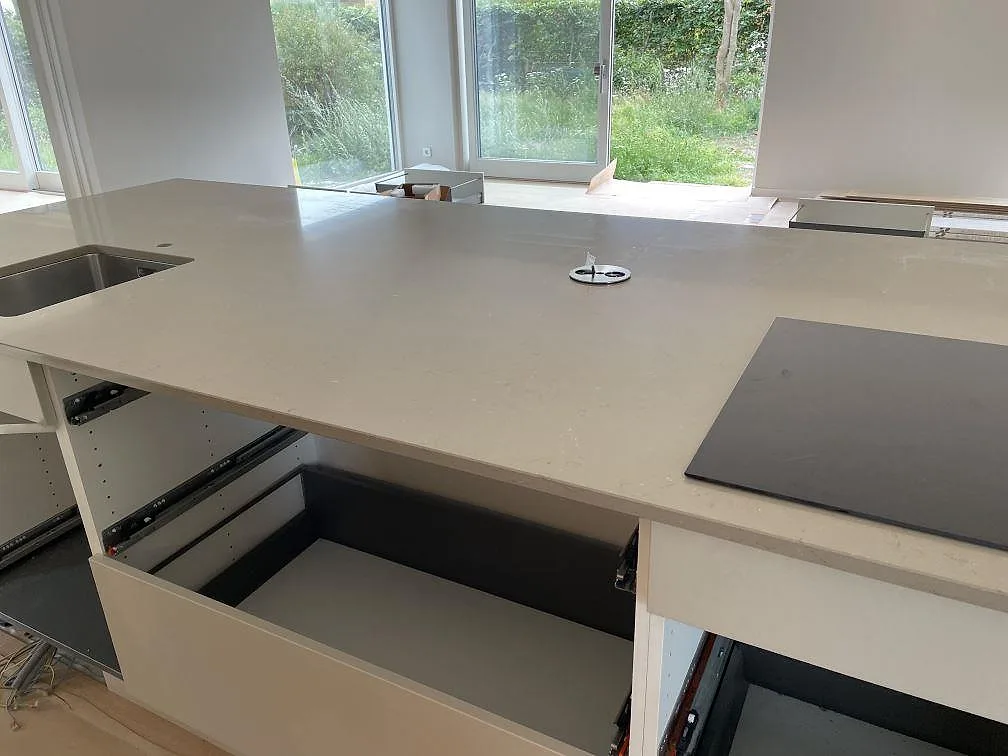 Närbild på köksö i Silestone Coral Clay komposit med polerad yta, synlig kant och svart induktionshäll i Bjärred.