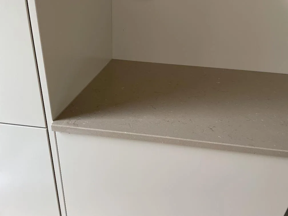 Detalj av sidobänk i polerad Silestone Coral Clay komposit mot vit köksinredning i Bjärred.