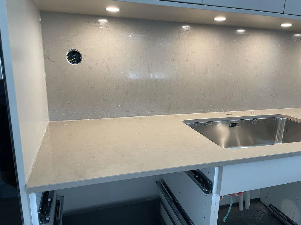 Bänkskiva och stänkskydd i polerad Silestone Coral Clay med rostfri underlimmad diskho under väggskåp i Bjärred.