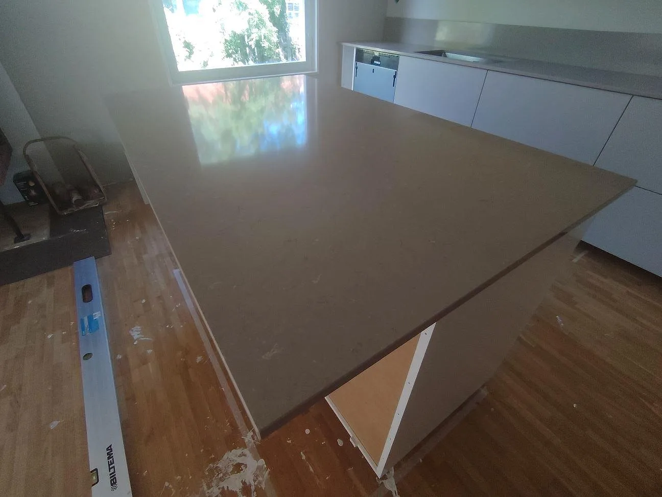 Polerad köksö i Silestone Coral Clay, varm gråbeige komposit, med bakre bänkskiva och underlimmad diskho i kök i Björklinge.