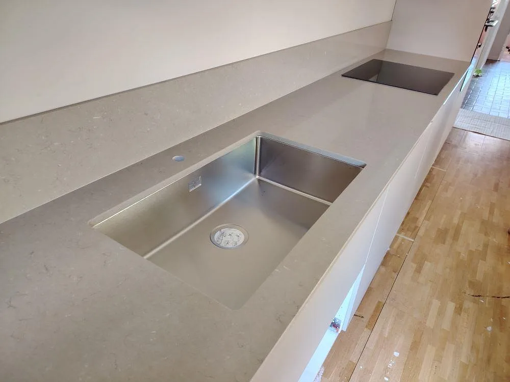 Närbild på polerad bänkskiva i Silestone Coral Clay med underlimmad rostfri diskho, svart häll och 12 mm stänkkant i Björklinge.