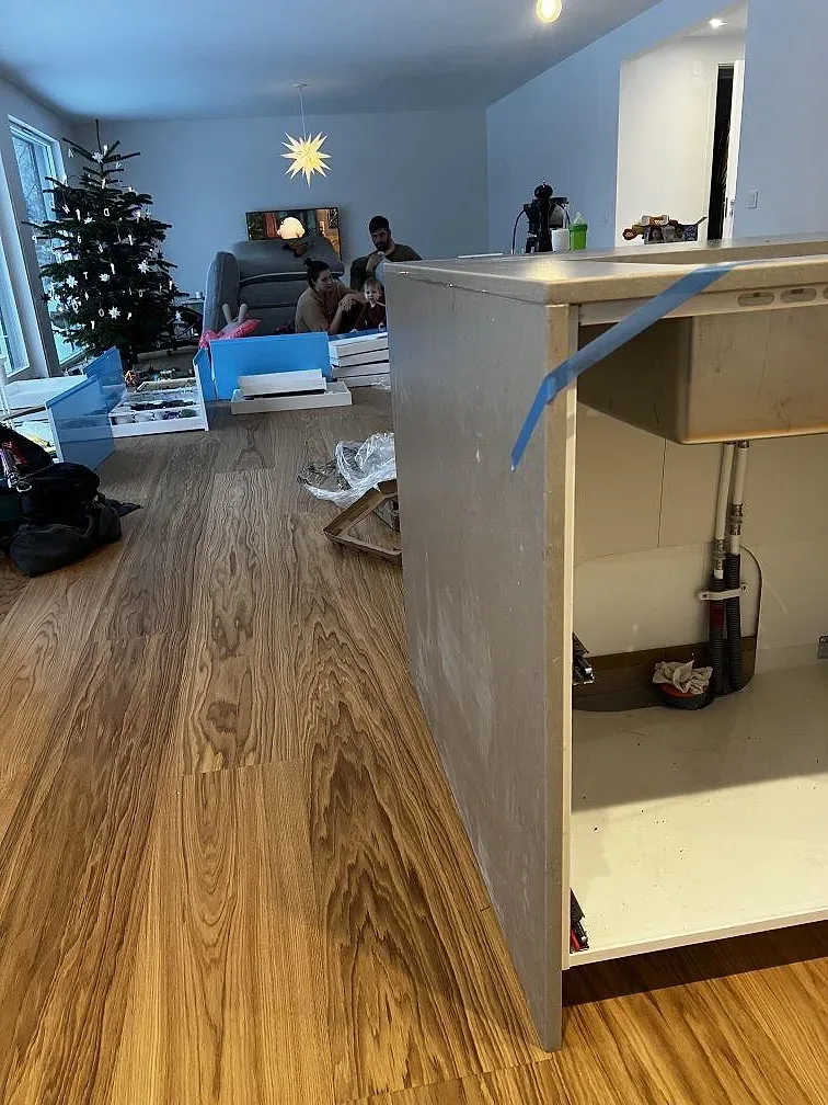 Sidovy av köksö med Silestone Coral Clay, öppen stomme och trägolv under montering i Borås.