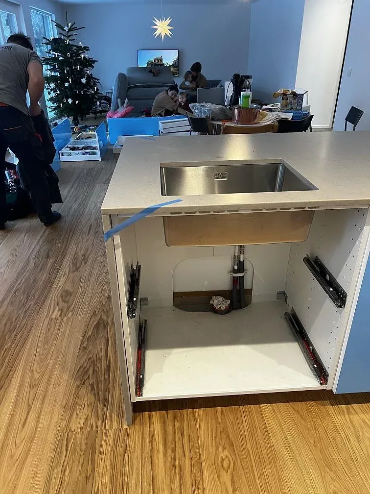 Köksö under montering med Silestone Coral Clay, rostfri diskho och öppen vit skåpstomme i Borås.