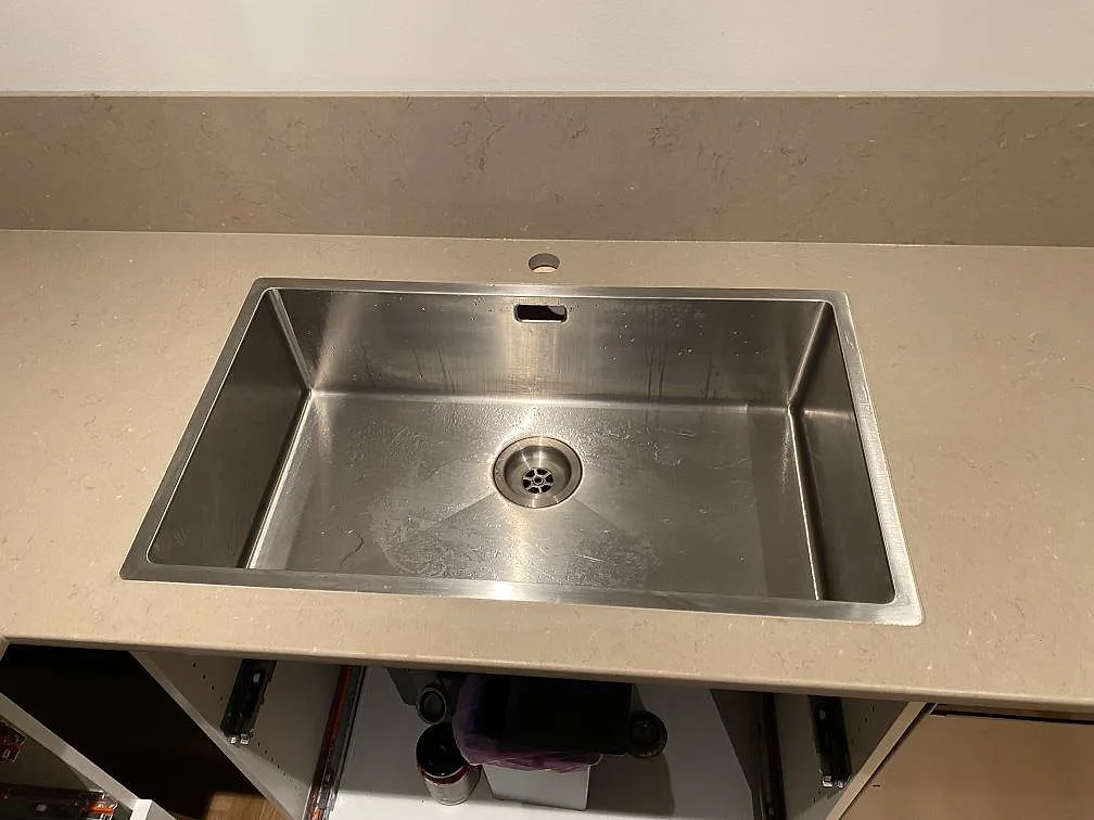 Närbild av diskho i en polerad köksbänkskiva i Silestone Coral Clay med uppvikt stänkkant i ett kök i Borås.