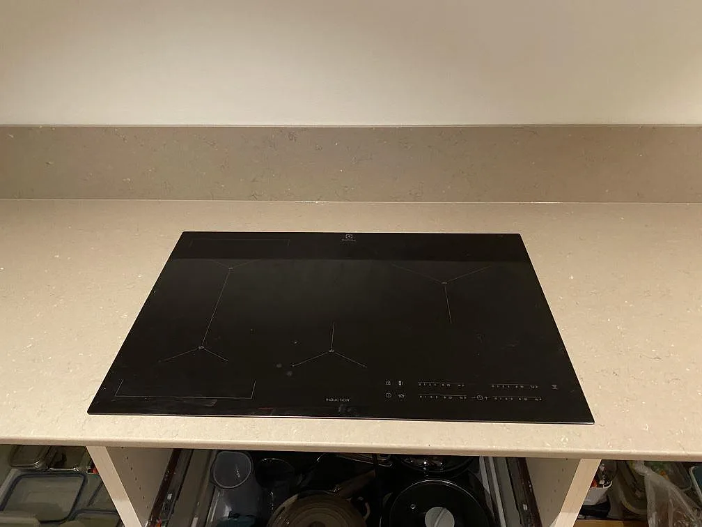 Infälld induktionshäll i polerad Silestone Coral Clay, varm gråbeige kompositbänkskiva med stänkkant i Borås.