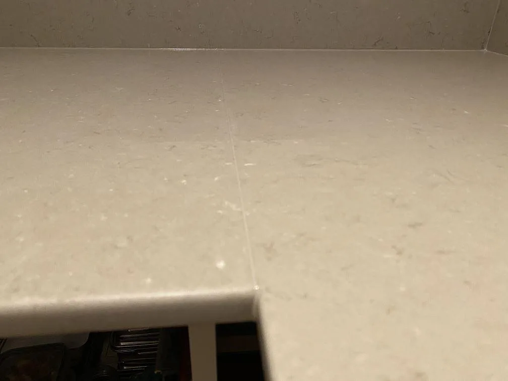 Detalj av skarv och framkant på polerad Silestone Coral Clay, gråbeige kompositbänkskiva med stänkkant i Borås.