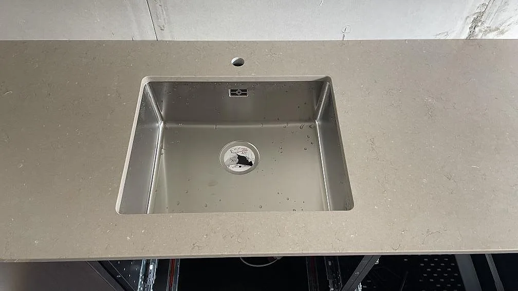 Närbild på rostfri diskho i polerad Silestone Coral Clay, 20 mm kompositbänkskiva i ett kök i Borås.