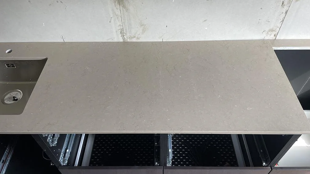 Lång arbetsyta i polerad Silestone Coral Clay komposit mellan diskho och hällurtag under köksmontering i Borås.