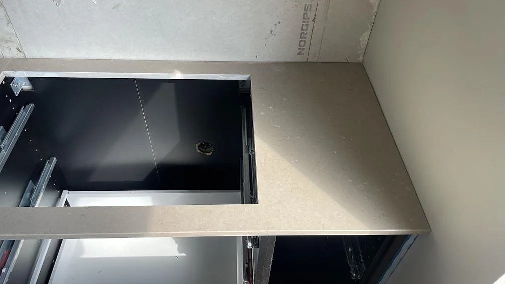 Höger avslut av polerad Silestone Coral Clay köksbänkskiva med hällurtag och varm beigegrå ton i Borås.