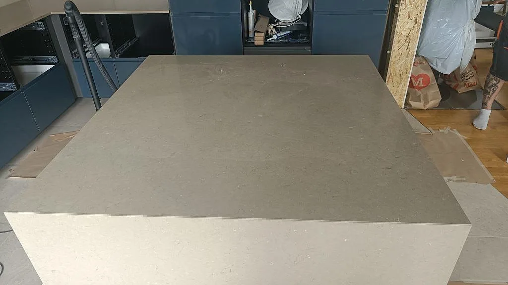Köksö i polerad Silestone Coral Clay i taupe kvartskomposit, fotograferad ovanifrån i ett kök under montering i Bunkeflostrand.